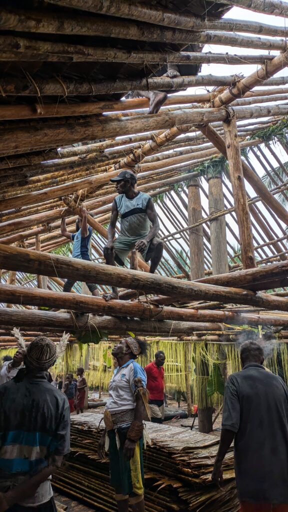 Community members constructing an Asmat longhouse in Papua, Indonesia